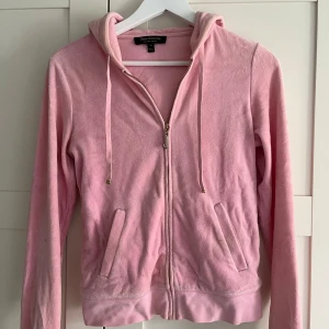 Rosa hoodie från Juicy Couture - Säljer en mysig rosa hoodie från Juicy Couture med dragkedja och huva. Perfekt för en avslappnad stil. Den har långa ärmar och praktiska fickor framtill. Hör av dig vid intresse! 💖