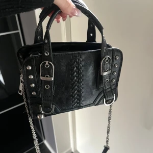 Svart väska Zara - Supersnygg svart väska från Zara som både går att ha som handväska och axelremsväska. Väskan har dragkedja en kedja som går att ta av om man vill! Jättebra skick det enda är att kedjan har vikt sig lite på ett ställe, se sista bilden