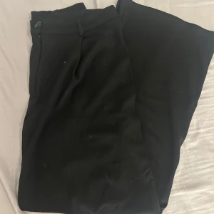 Svarta kostymbyxor från Nelly - Snygga svarta kostymbyxor från Nelly med knapp och dragkedja framtill. Super mjukt material men säljes då som inte används längre