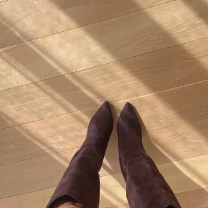 Bruna mockastövlar med dragkedja - Snygga bruna stövlar i mocka med dragkedja på sidan och spetsig tå. Perfekta för att ge en elegant touch till din outfit.