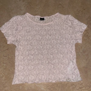 Rosa spetsblus från Gina Tricot - Säljer en söt rosa spetsblus från Gina Tricot. Blusen har korta ärmar med blommigt mönster, sitter på som en vanlig tröja i storlek M.