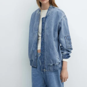 Blå jeans bomberjacka med dragkedja - Säljer en blå bomberjacka i jeansmaterial med dragkedja framtill och cool detaljficka på ärmen. Jackan har en loose passform och ribbade muddar vid midja och ärmslut. Jackan är i väldigt bra skick och säljer pga att jag vill köpa en annan💞💞