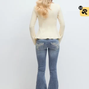 Blå bootcut jeans med broderi - Snygga blå bootcut jeans med slitningar och broderade detaljer på bakfickorna. Jeansen har låg midja. Använda 2 gånger. Passar bra på mig som vanligtvis bör M