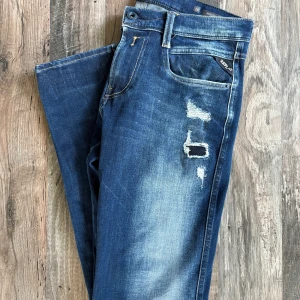 Replay Anbass jeans med slitningar - Säljer ett par Replay Anbass jeans med otroligt snygga slitningar. Jeansen är i nyskick och man ser inga spår av änvändning! De är endast änvända ett fåtal gånger och är i storleken 28/30. Hör av dig vid mer frågor😊