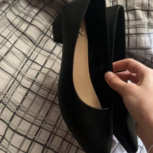 Svarta pumps från Clou, storlek 39 - Stilrena klackar från clou med spetsig tå och låg, bred klack. Skorna är i slätt material och har en klassisk design som passar till många olika outfits. Perfekta för dig som gillar en enkel men elegant look. Helt oanvända!💕
