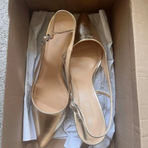 Guldiga pumps från Anna Field - Snygga pumps i guld från Anna Field med spetsig tå och smal rem runt hälen. Skorna har låg klack som är 6cm så lätta att gå i. Använda en gång på min bal