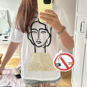 Vit t-shirt med grafiskt tryck - Vit t-shirt med oversized passform och svart grafiskt tryck framtill. T-shirten har korta ärmar och är gjord i mjuk bomull, perfekt för en chill och avslappnad stil. Passar snyggt till jeansshorts eller baggy byxor.