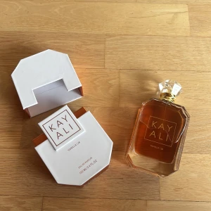 Kayali Vanilla | 28 Eau de Parfum 100ml - Oöppnad!!Kayali Vanilla | 28 Eau de Parfum i en stilren vit, åttakantig kartong med bronsfärgade detaljer. Doften har noter av vaniljorkidé, tonkaböna, brunt socker, amberträ och mysk. Flaskan rymmer 100 ml och är en del av Huda Beauty.