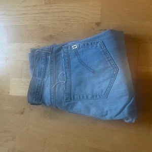 Ljusblå dondup jeans - Säljer ett par klassiska ljusblå jeans från dondup med raka ben. Jeansen har en snygg tvätt och subtila slitningar för en avslappnad look. Perfekta till sneakers eller boots och funkar året runt. Materialet är mjukt jeans i bomull.