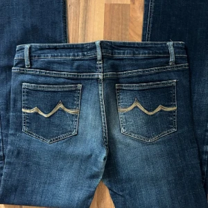 Mörkblå jeans - Snygga mörkblå jeans med klassisk femficksdesign och coola broderade detaljer på bakfickorna. Jeansen har raka ben och normal passform, tillverkade i slitstarkt denim med lätt tvättad look. Perfekta för dig som gillar stilrena och tidlösa jeans.