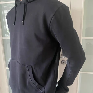 REA! Svart hoodie från J.Lindeberg – premium streetstil 🖤 - Svart hoodie från J.Lindeberg i strl M. Mjuk bomullsblandning, modern passform och stilig logga. Har ett hål vid halsen – fortfarande snygg passar lika bra till mjukisbyxor som jeans. ☑️Tidslös look - funkar alltid 🏷️ Nypris ca 1200 kr – NU 299 kr 📦 Gratis frakt hela veckan  🖤 Minimalistisk & clean – säkra den innan någon annan gör det!