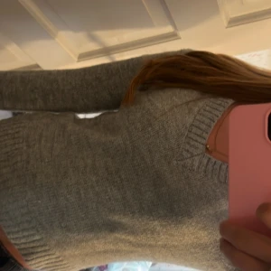 Grå stickad v-ringad tröja Gina Tricot - Mysig grå stickad tröja från Gina Tricot i storlek XS. Tröjan har v-ringad hals, ribbade muddar vid ärmslut och nederkant samt lång ärm. Perfekt att slänga på sig när det är kyligt ute. Enkel och stilren design som funkar till jeans eller kjol.