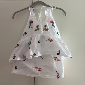 Volangtopp - Volangtopp med broderade blommor från Zara! Storlek xs och knyts i nacken