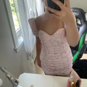 Rosa blommig kortklänning med paljetter - Supersöt ljusrosa kortklänning med blommigt mönster och glittriga paljetter. Klänningen har offshoulder puffärmar och är ifrån Shein ❤️