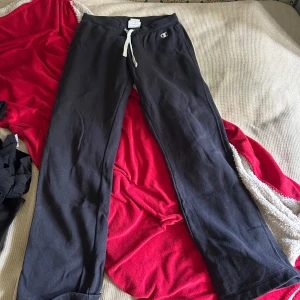 Svarta mjukisbyxor från Champion L - Svarta mjukisbyxor från Champion med Heritage Fit. Byxorna har vit snörning i midjan och klassisk Champion-logga på höften. Tillverkade i mjukt bomullsmaterial, perfekta för chill eller träning.