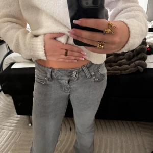 Grå lågmidjade jeans - Säljer ett par grå jeans med låg midja och bootcut. Jeansen har snygg broderad detalj på bakfickan och dubbla knappar i midjan. Helt nya och oanvända💓 storlek XXS, men passar mig som alltid har XS