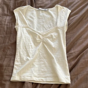 Vit linnetopp från 157, XS - Supersöt vit linnetopp från 157 i storlek XS. Toppen har en djup v-ringning med spetskant och snygg rynkdetalj framtill. Ärmlös och i mjuk bomull