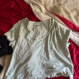 Ljusgrön ribbad topp från 157 - Säljer en ljusgrön ribbad topp från 157 i storlek XL. Toppen har korta ärmar, v-ringning och vågig kant nertill och vid ärmsluten. Perfekt för dig som gillar en enkel men ändå trendig stil.