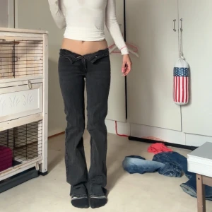 Svarta bootcut jeans med låg midja - Säljer ett par svarta jeans med låg midja och bootcut-ben. Jeansen har klassisk femficksdesign och är tillverkade i ett mjukt denimtyg. Snygg passform som sitter tajt upptill och släpper ut vid bensluten. Perfekta för en trendig och avslappnad look. Tyvärr får ja inte knäppt dem, men de är en liten bit under naveln