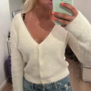 Vit fluffig kofta från Zara - Supermjuk och fluffig vit kofta från Zara med v-ringning och knappar framtill. Croppad modell med långa ärmar.