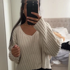Beige ribbad stickad tröja med v-ringning - Säljer en supermysig beige stickad tröja med breda ribbade ränder och v-ringad hals. Tröjan har långa ärmar med lite loose passform och är perfekt för att chilla eller hänga med vänner. Passar dig som gillar enkel och stilren vibe. Storlek L men passar M 