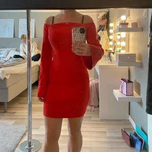 Röd offshoulder ribbad kortklänning - Säljer en snygg röd ribbad klänning med offshoulder och långa ärmar. Klänningen är kort och har en tight passform som framhäver figuren. Perfekt att ha på julen.