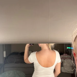 Vit topp med öppen rygg - Säljer en vit, tight topp med korta ärmar och rund halsringning framtill. Baksidan har en snygg djup, öppen rygg som ger en cool och stilren vibe. Perfekt att styla med jeans eller kjol för en trendig look.