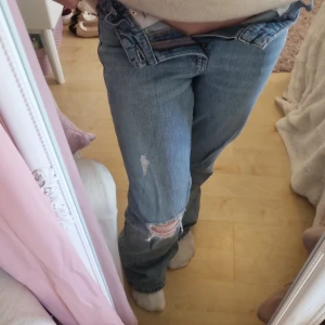 Ljusblå bootcut jeans med slitningar - Säljer ett par ljusblå jeans med bootcut passform och snygga slitningar på knäet och låret. Jeansen har klassisk femficksdesign, normal midja och är tillverkade i bomull. Använda ett fåtal gånger men i mycket bra skick förutom vissa fläckar som syns i annosen. Säljer de då är för små för mig. Nypris runt 150 kr.