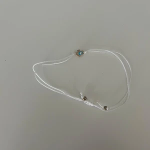 Vitt armband - Snyggt vitt armband i tunn tråd, Justerbar knut för perfekt passform. Perfekt accessoar för en cool och enkel stil.