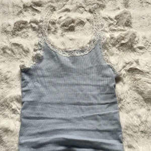 Ljusblå ribbad linnetopp med spets - Supersöt ljusblått linne med spets, mjukt material, storlek XXS, pris 15kr.