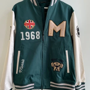 Grön och vit bomberjacka från Morris - Köp flera plagg för rea! • Helt ny bomberjacka (Ramsey Jacket) från Morris i grönt med vita ärmar. Jackan har broderade patches, stora som små. Perfekt för dig som gillar en snygg och trendig stil. Storlek S, passar dig mellan 170-180 cm lång!