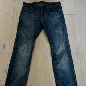 Blå jeansbyxor i rak modell, 29/32 - Snygga blå jeansbyxor i klassisk rak modell med slitningar och kontrastsömmar. Jeansen har fem fickor och coola detaljer på bakfickorna. Perfekta för dig som gillar en avslappnad men stilren look.