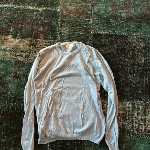 Ljusblå tröja från Tailored Originals - Säljer en stilren ljusblå tröja från Tailored Originals. Tröjan har en klassisk design med långa ärmar och rund halsringning. Perfekt för en avslappnad look.