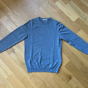 Grå merinoulltröja - Säljer en stilren grå tröja i 100% merinoull. Tröjan har en rund hals och långa ärmar, perfekt för kyligare dagar. Den är mjuk och bekväm, idealisk för både vardag och mer uppklädda tillfällen.