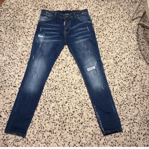 Blå jeans från Dsquared2 - Snygga blå jeans från Dsquared2 med slitna detaljer och en klassisk femficksdesign. De har en knappgylf och kontrasterande sömmar som ger en cool look. Perfekta för en avslappnad stil.