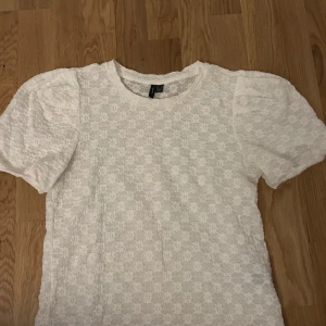 Vit blus med puffärmar - Säljer en söt vit blus med puffärmar och ett blommigt mönster. Blusen har en rund halsringning och är perfekt för en somrig look. Den är tillverkad i ett lätt och luftigt material som ger en romantisk känsla. Tyvärr så har den är fläck runt nacken