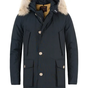 Svart parkajacka med pälsdetalj - Snygg svart parkajacka från Woolrich med pälsdetalj på huvan. Jackan har knappar och dragkedja framtill samt praktiska fickor. Perfekt för kyliga dagar.