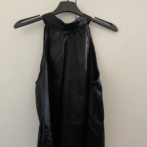 Svart ärmlös topp  - Snygg svart ärmlös topp i ett glansigt material. Har använt den en gång och kommer inte till användning längre så därav säljer jag den💗💗