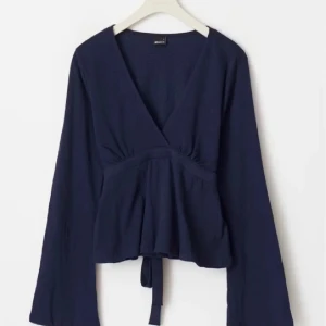 Mörkblå omlottopp med knytband - Snygg mörkblå omlottopp från gina med långa ärmar och knytband i midjan. Perfekt för en stilren look, inga defekter!!💞💞