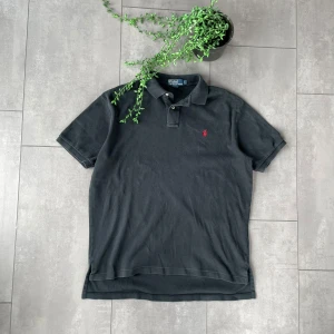Svart pikétröja från Ralph Lauren - Säljer en klassisk Ralph Lauren piké i svart. Storlek L, i mycket bra skick och knappt använd.  ✔️ Stilren och tidlös design ✔️ Högkvalitativt material för en bekväm passform ✔️ Ikoniska Polo Ralph Lauren-loggan på bröstet  Perfekt både till vardags och mer uppklädda tillfällen. Skickas snabbt efter köp – hör av dig vid frågor!