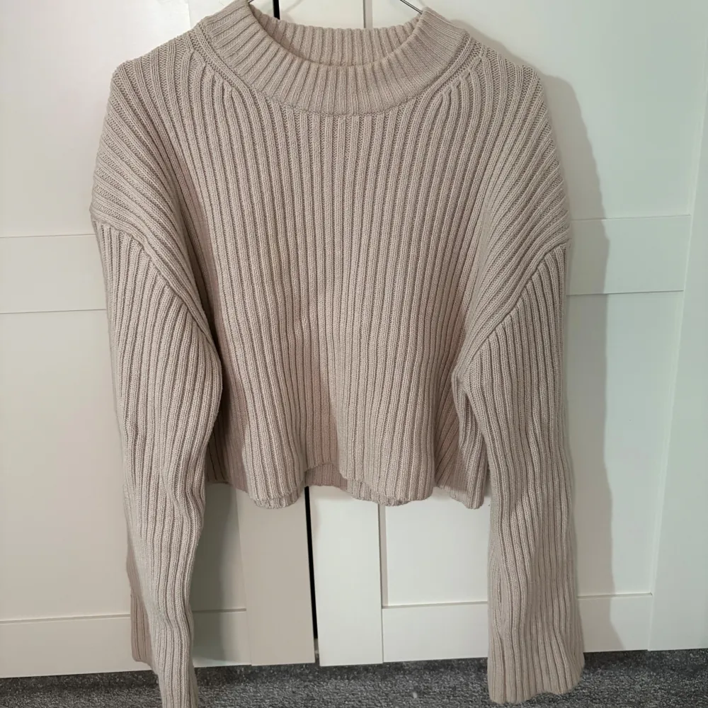 Säljer en stilren beige ribbad tröja från H&M. Tröjan har en croppad passform och långa ärmar, perfekt för en avslappnad look. Den är tillverkad i ett mjukt material som gör den bekväm att bära. Passar utmärkt till både jeans och kjol.. Neuletakit & Villapaidat.