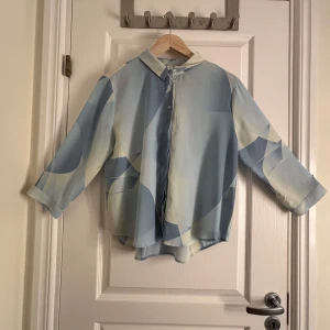 Blå skjorta från Monki - Säljer en skjorta från Monki som är i olika nyanser av blå. Tunt material perfekt till sommaren och det härliga varma vädret☀️