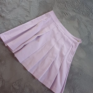 Ljuslila kjol från Divided - Säljer en söt ljuslila kjol från Divided. Kjolen har en plisserad design och en praktisk dragkedja i sidan. Perfekt för att ge en färgklick till din outfit! 💜 liten skada i sömmen