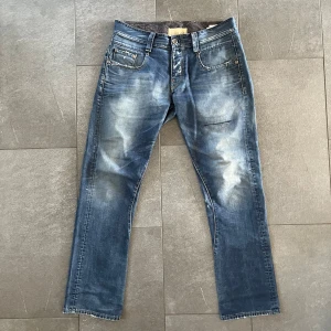 G-Star RAW jeans - Snygga blå jeans från G-Star RAW med slitningar och unika broderade stjärnor på bakfickan. De har en klassisk femficksdesign och knappar i gylfen. Perfekta för en avslappnad stil. Hör av er vid frågor priset går att diskutera.