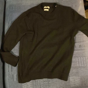 Svart tröja - Säljer en stilren svart tröja med långa ärmar. Perfekt för en minimalistisk look. Tröjan har en klassisk design med ribbstickade muddar vid ärmslut och nederkant. Storlek S men sitter som XS