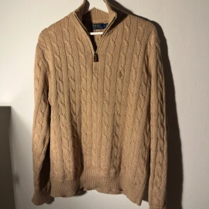   Ralph Lauren tröja  - Säljer en stilren stickad tröja från Ralph Lauren med kabelstickat mönster och dragkedja vid halsen. Skicket är bra och den är självklart äkta. kontakta gärna mig vid frågor