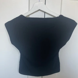 Svart offshoulder topp - Snygg svart offshoulder topp med öppen rygg. Perfekt för en stilren look. Är från Shein men aldrig använd. Passar jeans och kjol och är i stolek 14 years old är som en (XS)