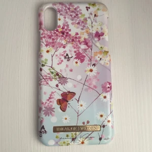 Mobilskal Springtime Whimsy från iDeal of Sweden - Säljer ett snyggt mobilskal från iDeal of Sweden med ett vårigt blommönster i rosa, lila och gröna nyanser. Skalet är designat för iPhone X och har en elegant finish med fjärilar och blommor. Perfekt för att ge din telefon en fräsch look! JätteLite rostig på insidan men inget som syns eller påverkar.