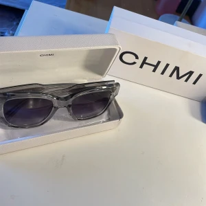 Grå  solglasögon från Chimi i modellen 07 - Snygga grå solglasögon från Chimi med transparent båge och mörka linser. I modellen 07. Kommer i originalförpackning.