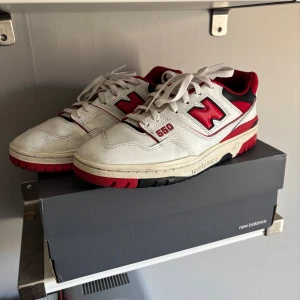 New Balance 550  - Snygga New Balance 550 sneakers i vitt och rött med svarta detaljer. Skorna har en klassisk design med snörning och en bekväm passform. Perfekta för en sportig look. Det kommer med ett kvitto direkt från junk yard Stockholm.